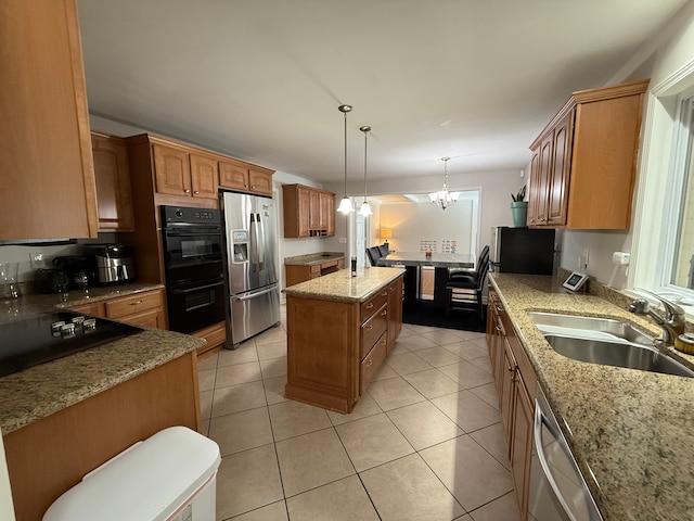 kitchen featuring sink, black appliances, decorative light fixtures, an inviting chandelier, and a center island