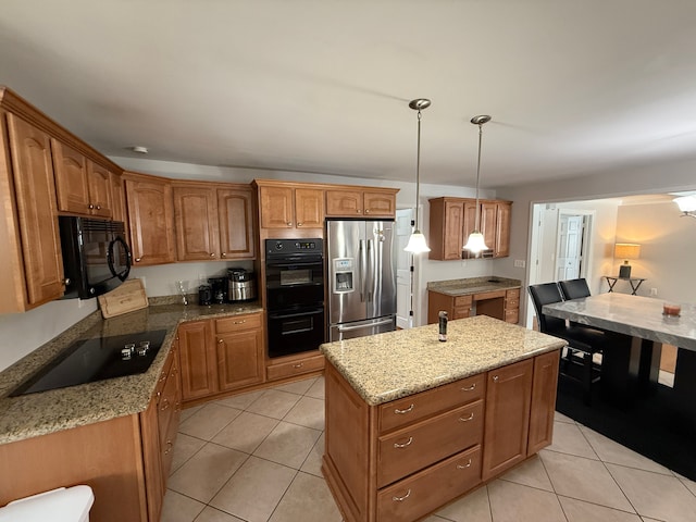 kitchen featuring a center island, light stone counters, pendant lighting, light tile patterned flooring, and black appliances