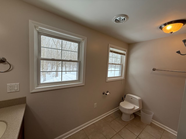 bathroom featuring toilet, vanity, tile patterned floors, and a wealth of natural light