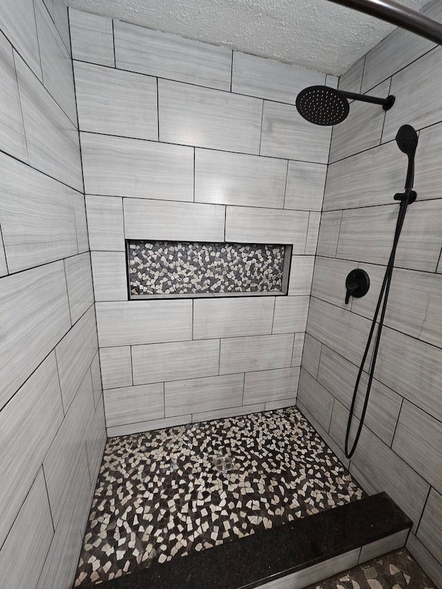 bathroom featuring a textured ceiling and tiled shower