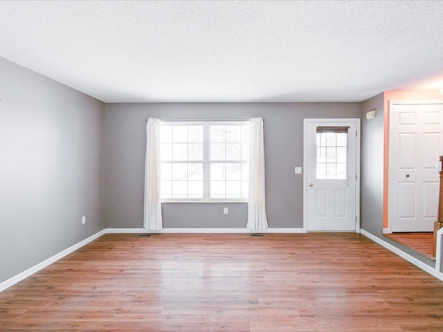 entryway with light hardwood / wood-style floors and a textured ceiling