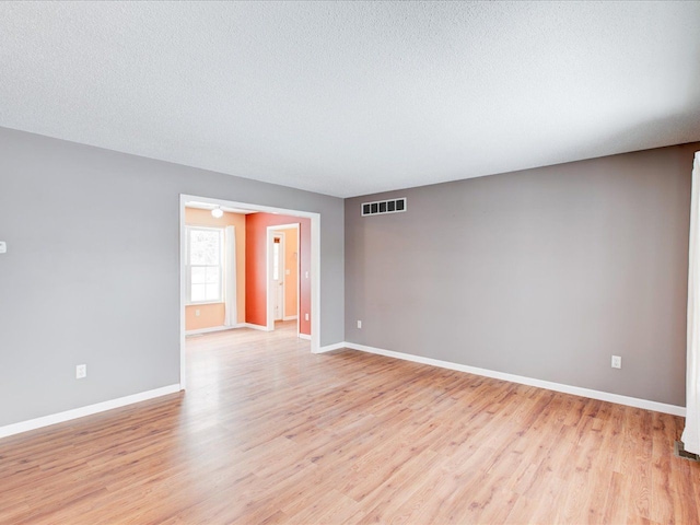 unfurnished room with a textured ceiling and light wood-type flooring