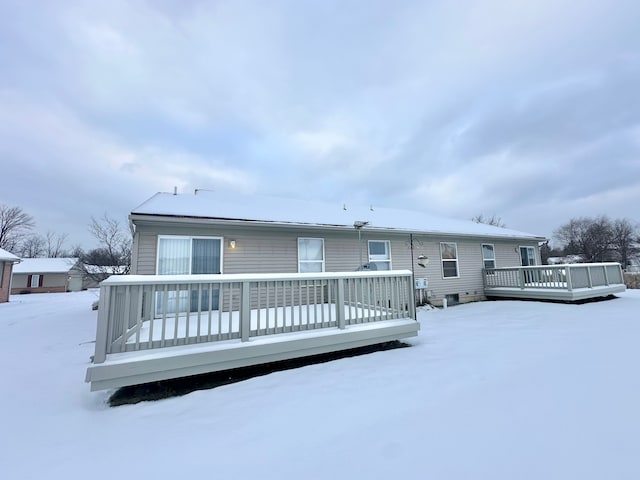 snow covered rear of property with a deck