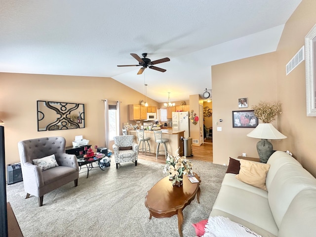 carpeted living room featuring vaulted ceiling and ceiling fan with notable chandelier