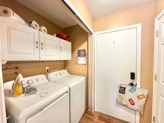 clothes washing area with a textured ceiling, cabinets, light hardwood / wood-style flooring, and washing machine and clothes dryer