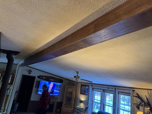 details featuring a textured ceiling, a ceiling fan, and beamed ceiling