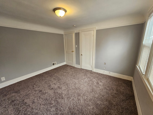 unfurnished bedroom with a closet, ornamental molding, and carpet