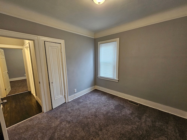 unfurnished bedroom with ornamental molding and dark carpet