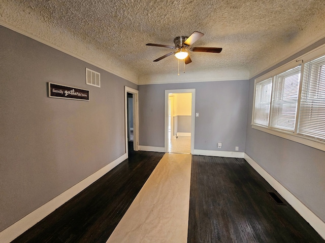 spare room featuring dark hardwood / wood-style flooring, a textured ceiling, ornamental molding, and ceiling fan