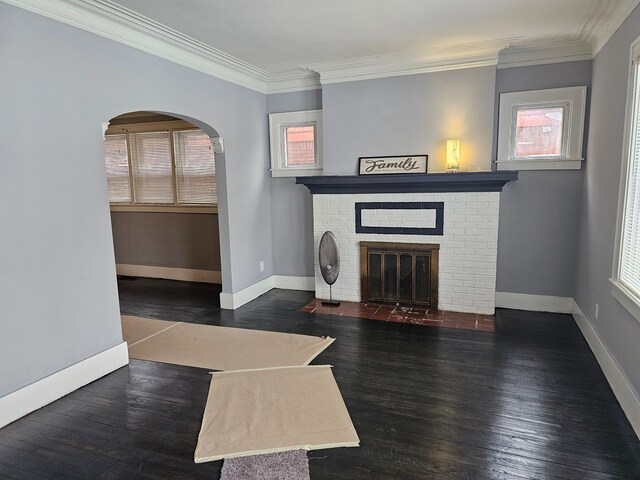 unfurnished living room with a brick fireplace, dark wood-type flooring, and crown molding