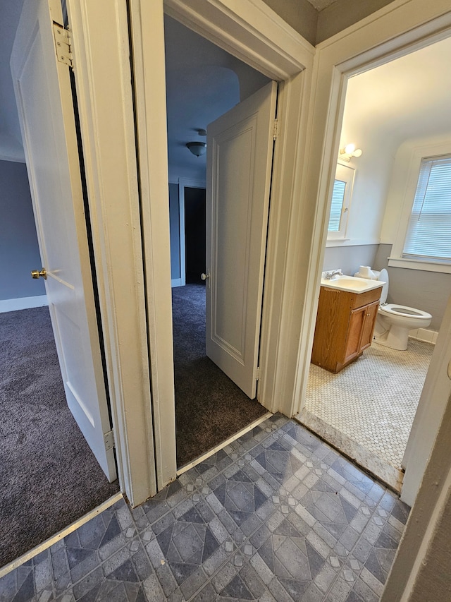 hallway featuring sink and dark colored carpet