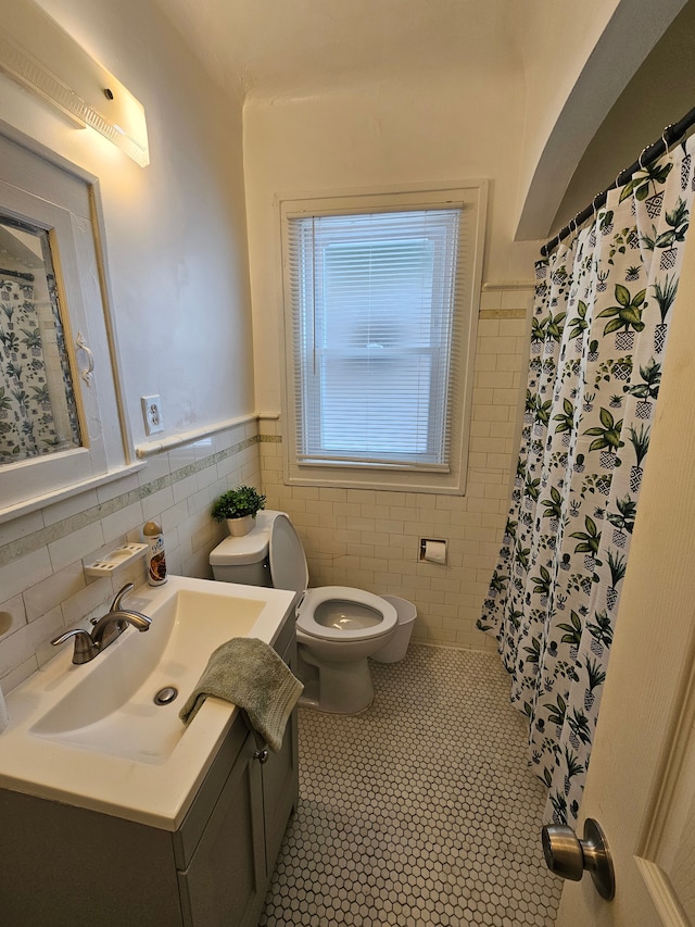 bathroom with curtained shower, tile walls, tile patterned flooring, vanity, and toilet