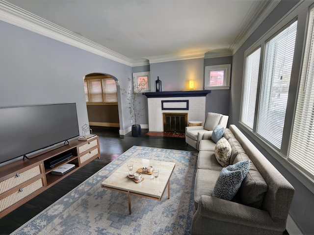 living room with dark hardwood / wood-style flooring, a brick fireplace, and crown molding