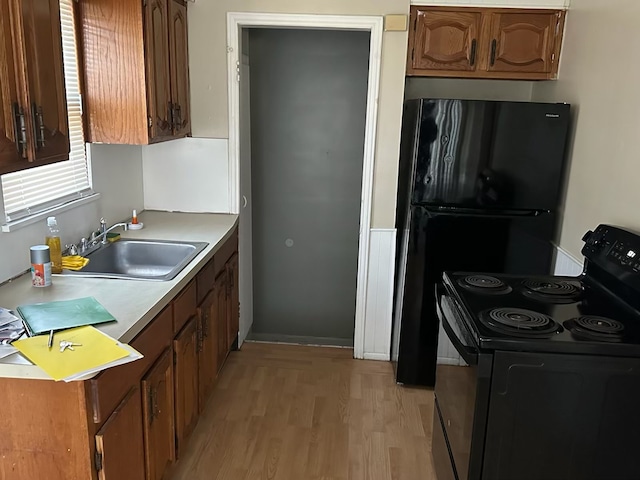 kitchen featuring black electric range oven, light wood-type flooring, and sink