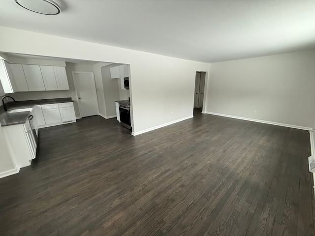 unfurnished living room with sink and dark wood-type flooring