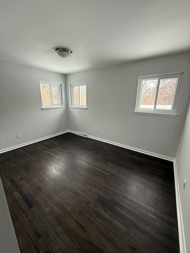 empty room with plenty of natural light and dark wood-type flooring