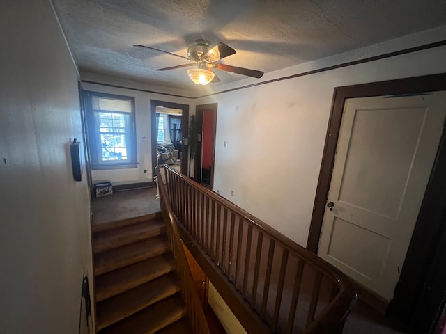 staircase with a textured ceiling and ceiling fan