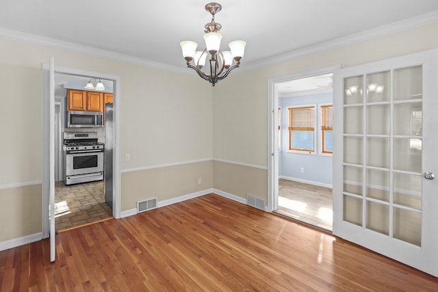 unfurnished dining area featuring crown molding, hardwood / wood-style floors, and an inviting chandelier