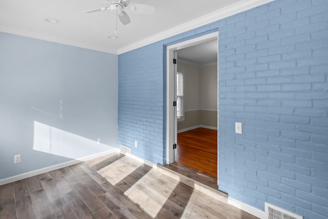 unfurnished room featuring wood-type flooring, brick wall, crown molding, and ceiling fan