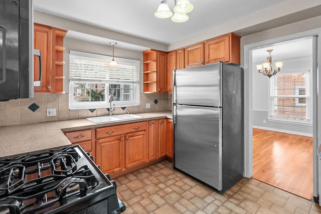 kitchen with decorative backsplash, sink, appliances with stainless steel finishes, and an inviting chandelier