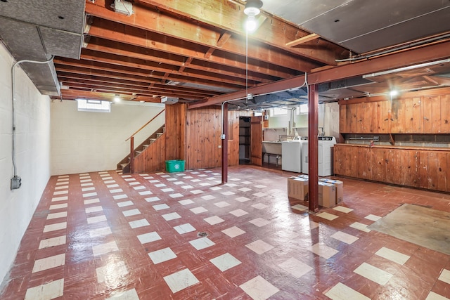 basement with washer and clothes dryer and wood walls