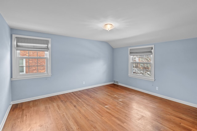 spare room featuring vaulted ceiling and light wood-type flooring