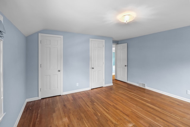 unfurnished bedroom featuring vaulted ceiling and wood-type flooring