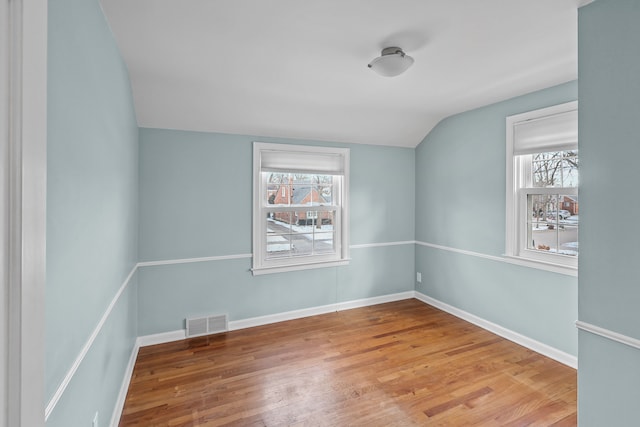 empty room featuring wood-type flooring and vaulted ceiling