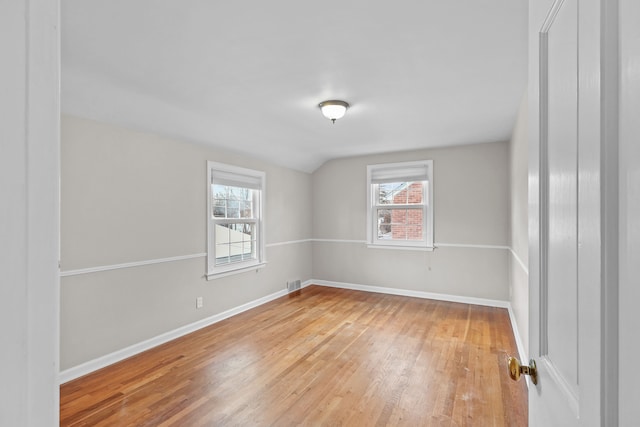 empty room featuring hardwood / wood-style flooring, a healthy amount of sunlight, and lofted ceiling