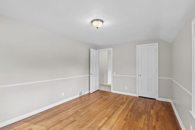 unfurnished bedroom featuring hardwood / wood-style floors and lofted ceiling