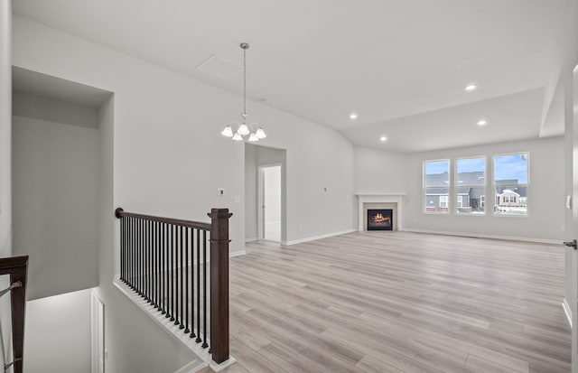 unfurnished living room with light hardwood / wood-style floors and a notable chandelier