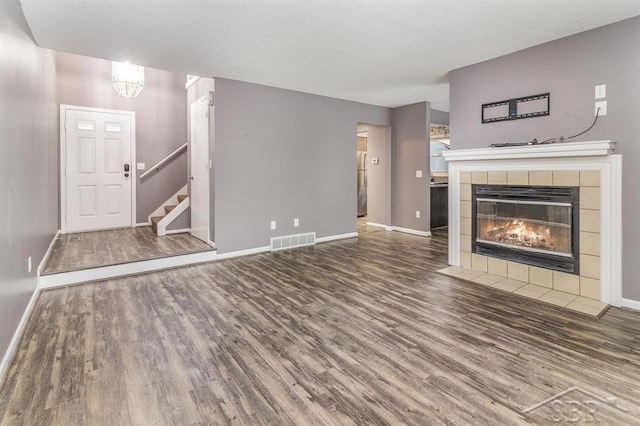 unfurnished living room featuring a tiled fireplace and wood-type flooring