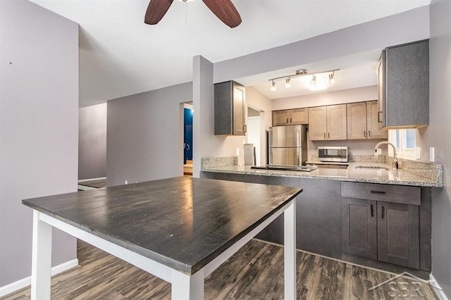 kitchen featuring dark wood-type flooring, sink, ceiling fan, appliances with stainless steel finishes, and light stone counters