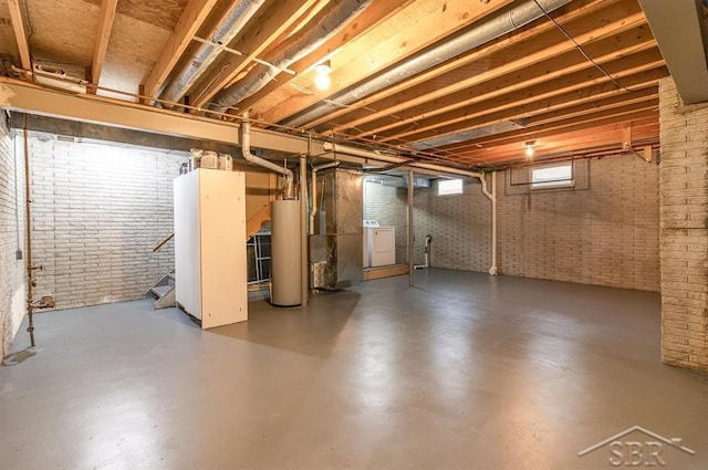 basement featuring washer / clothes dryer, brick wall, and gas water heater