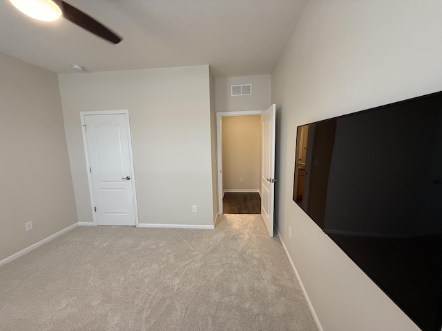 unfurnished bedroom featuring ceiling fan, a closet, and light carpet