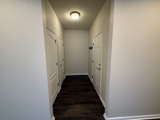 corridor with dark hardwood / wood-style floors and a textured ceiling