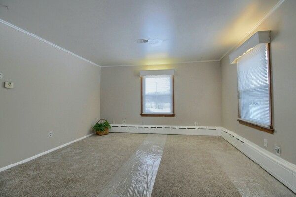 empty room featuring carpet flooring, baseboard heating, and ornamental molding