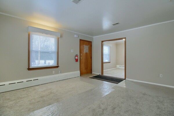 empty room featuring a baseboard heating unit and crown molding