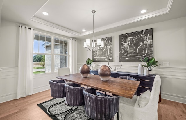 dining room featuring a tray ceiling, an inviting chandelier, and light wood-type flooring