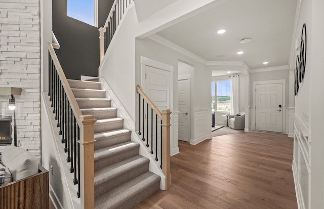 entrance foyer with crown molding, a fireplace, and dark wood-type flooring