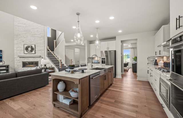 kitchen with white cabinets, appliances with stainless steel finishes, decorative backsplash, and an island with sink