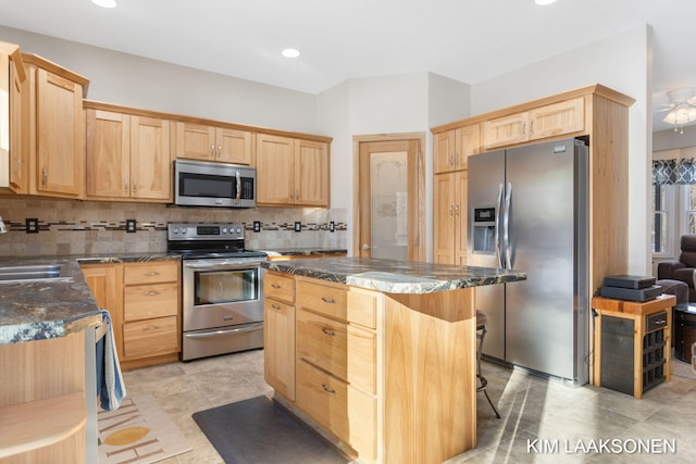 kitchen with a kitchen breakfast bar, sink, decorative backsplash, a kitchen island, and stainless steel appliances