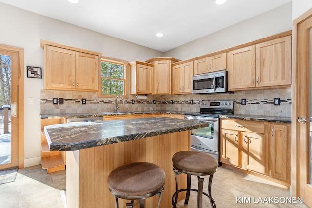 kitchen with dark stone counters, sink, a kitchen island, and stainless steel appliances