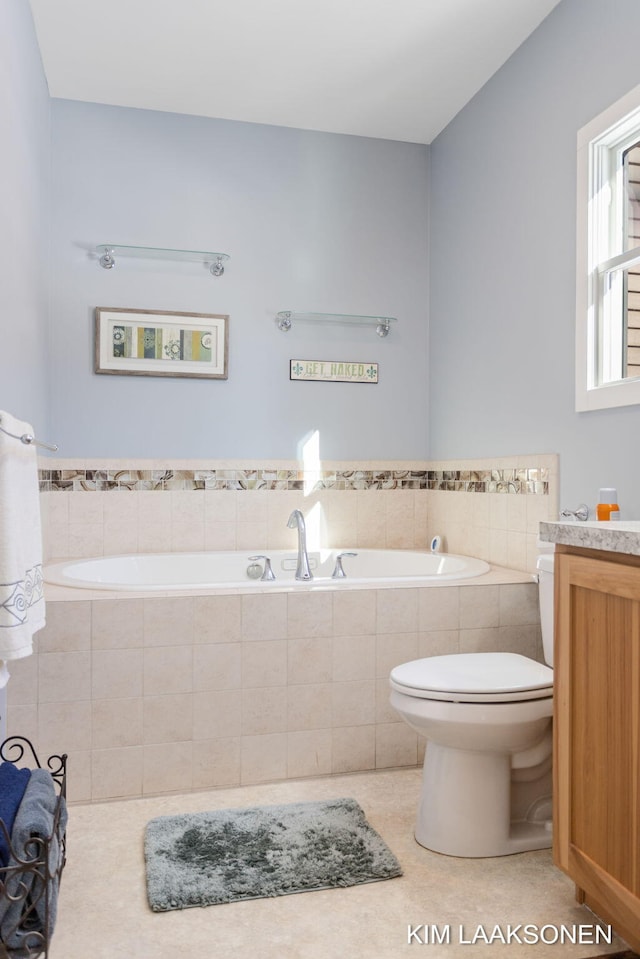 bathroom with toilet, vanity, tiled bath, and tile patterned floors