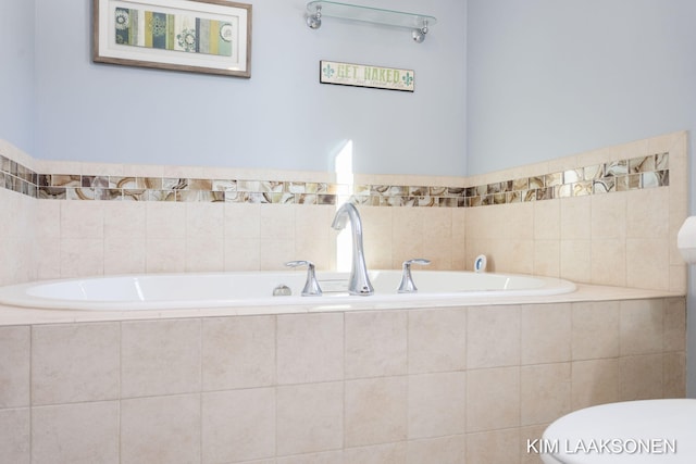 bathroom featuring toilet and tiled tub