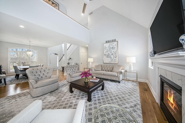 living room featuring a chandelier, dark hardwood / wood-style floors, high vaulted ceiling, and a tiled fireplace