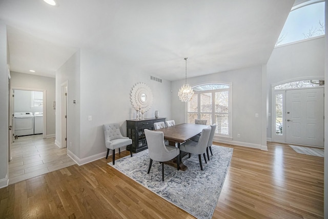 dining space featuring washing machine and dryer, an inviting chandelier, and light wood-type flooring