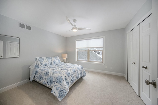 bedroom with ceiling fan, light carpet, and a closet