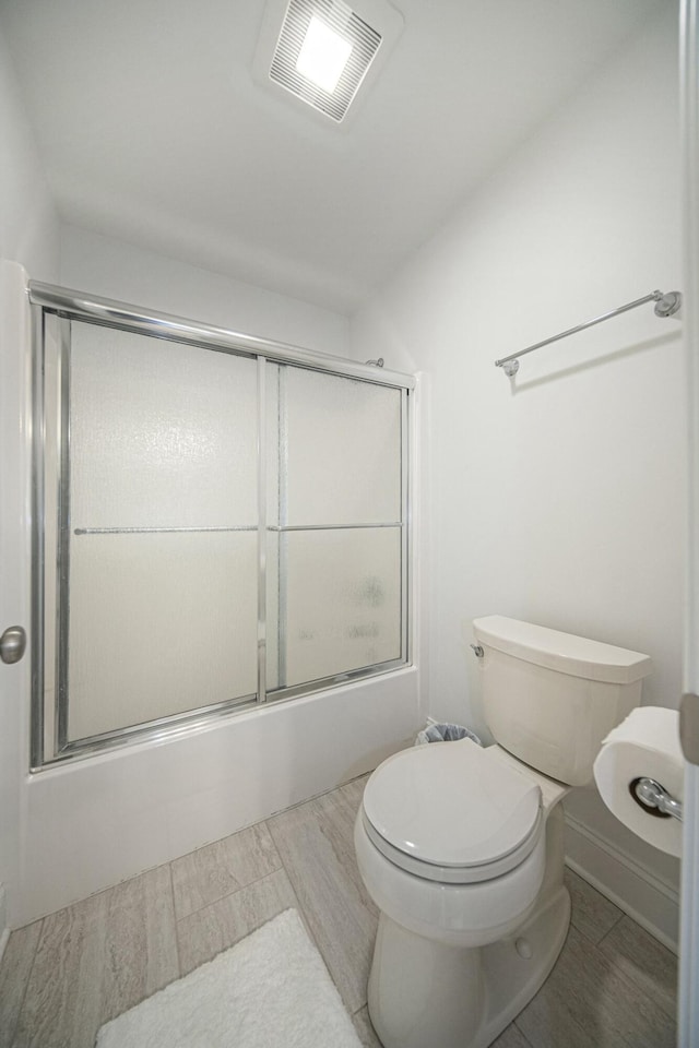 bathroom with combined bath / shower with glass door and toilet