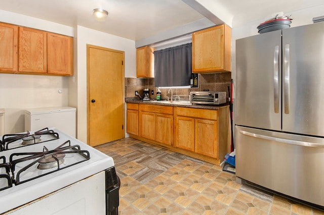 kitchen with sink, backsplash, white gas range oven, and stainless steel refrigerator